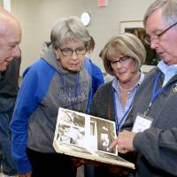 Four alumni look through the 1968 yearbook.